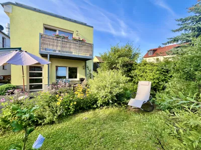Garten hinter dem Haus mit Rasenfläche, Sonnenschirm und Liegestuhl vor dem Nachbargebäude.