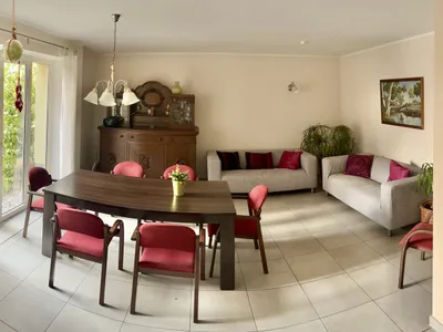 Gemeinschaftsraum mit langer Tafel, roten Polsterstühlen und einer alten Anrichte, daneben eine Sitzgruppe.